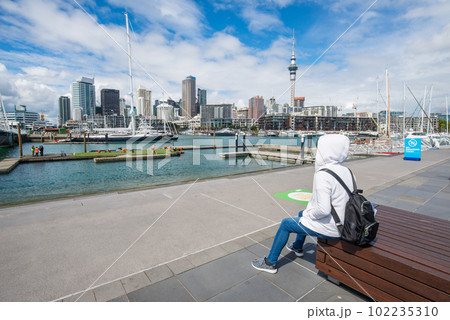 Tourist relax by sitting at waterfront and looking to the beautiful cityscape of Auckland the largest city in New Zealand. Tourist relax by sitting at waterfront and looking to the beautiful cityscape of Auckland the largest city in New Zealand. 102235310