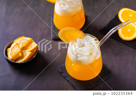 Dirty orange soda with whipped cream in glasses and orange slices on the table Dirty orange soda with whipped cream in glasses and orange slices on the table 102235364