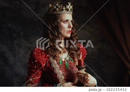 medieval queen in red dress with candle and crown 102235432