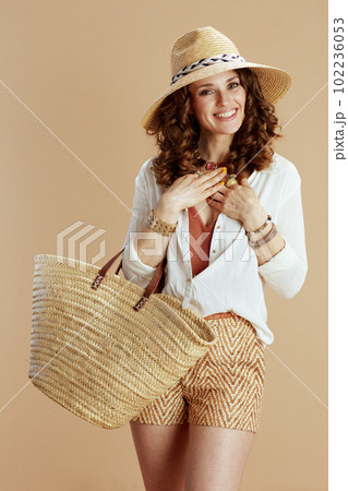 smiling housewife in blouse and shorts on beige 102236053
