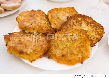 Fried grated potato pancakes with sour cream on white plate Fried grated potato pancakes with sour cream on white plate 102236291