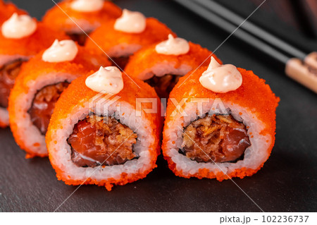 Sushi roll with tuna, onion in batter and tobiko caviar served on black board close-up - Japanese food Sushi roll with tuna, onion in batter and tobiko caviar served on black board close-up - Japanese food 102236737
