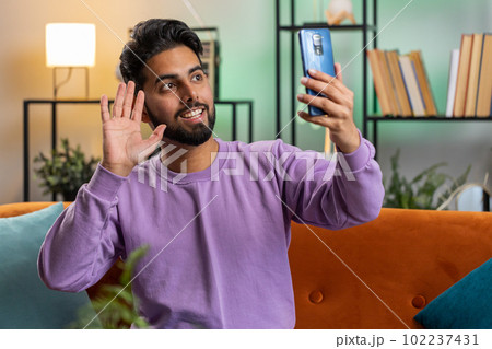 Indian man blogger taking selfie on smartphone recording vlog stories for social media subscribers 102237431