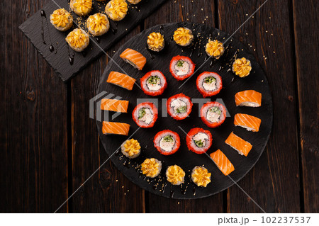 Sushi set from top on black background close-up. An assortment of various maki nigiri and rolls seafood soy sauce Sushi set from top on black background close-up. An assortment of various maki nigiri and rolls seafood soy sauce 102237537