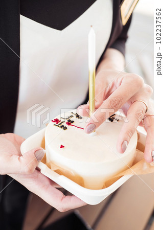 Bento cake with a candle with a girl's hand,close-up.Little surprise for a girl's birthday 102237562