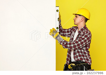 smiling professional builder in work clothes in helmet with level . smiling professional builder in work clothes in helmet with level . 102237996