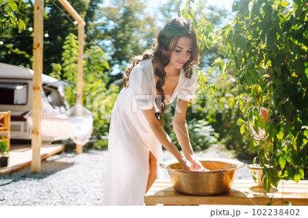 Beautiful stylish bride near trailer. Camping season. Marriage. Happy newlywed woman. 102238402