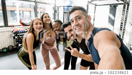Cheerful diverse sportspeople doing selfie at gym 102238621