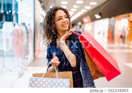 Smiling woman with shopping bags enjoying shopping in the mall.Young woman with packages after shopping. 102238905