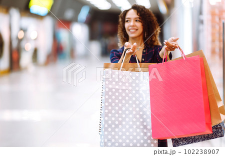Young woman after shopping with shopping bags walks in the mall. Spring shoopping. Young woman after shopping with shopping bags walks in the mall. Spring shoopping. 102238907