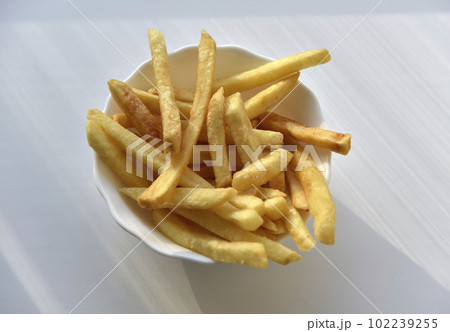Slices of French fries on a white plate. Delicious fried potatoes. Fast food. 102239255