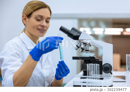 Attractive female scientist examining liquid in test tube in laboratory, doing DNA researching 102239477
