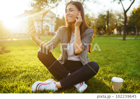The girl holds the phone and coffee in hand. Sunset. Summertime. The girl holds the phone and coffee in hand. Sunset. Summertime. 102239645