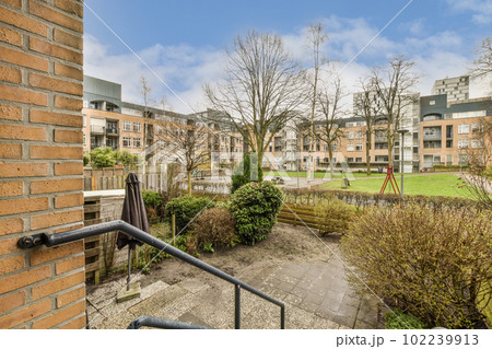 an outside area with trees and bushes in the foreground, taken from a window looking out onto some buildings an outside area with trees and bushes in the foreground, taken from a window looking out onto some buildings 102239913