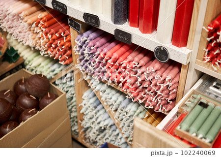 Many multicolored colorful paraffin stick Pastel colors candles arranged in shelves lying on shelter and sorted by color in a household candle shop store market. 102240069