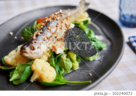 Roasted pike perch or cod fish with baked vegetables and spinach. Dish decorated with a slice of lemon. Restaurant menu Roasted pike perch or cod fish with baked vegetables and spinach. Dish decorated with a slice of lemon. Restaurant menu 102240072