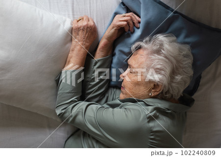 Senior woman sleeping in her bed, top view. 102240809