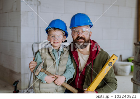 Portrait of father and his little son in their unfinished house. Portrait of father and his little son in their unfinished house. 102240823