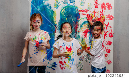 Portrait of happy kids with finger colours and painted t-shirts, studio shoot. 102241084