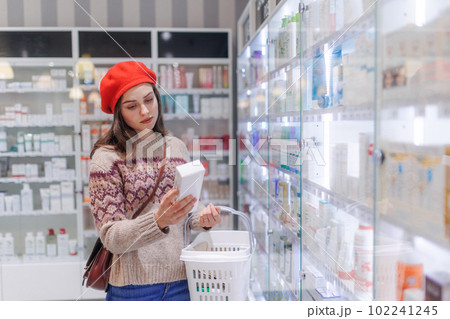 Young woman choosing a medication in pharmacy store. 102241245
