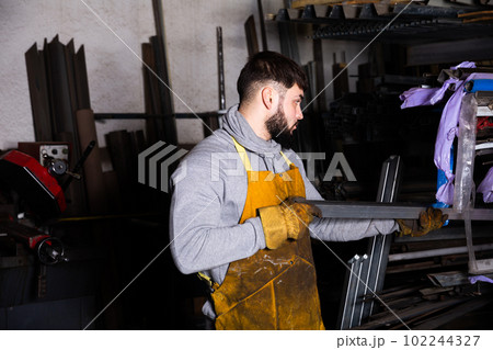 Portrait of man looking at profile steel tube 102244327
