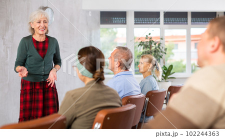 Mature female professor giving lecture to elderly students 102244363