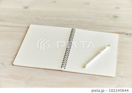木目のデスクに広げられた新しいノートとボールペン 102245644