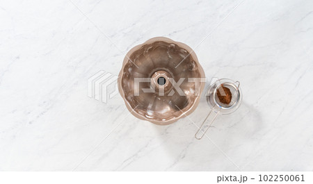 Flat lay. Greasing metal bundt cake pan with vegetable shortening and cocoa powder to bake gingerbread bundt cake with caramel filling. Flat lay. Greasing metal bundt cake pan with vegetable shortening and cocoa powder to bake gingerbread bundt cake with caramel filling. 102250061