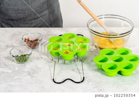 Filling silicone molds with egg mixture to make egg bites in a pressure cooker. Filling silicone molds with egg mixture to make egg bites in a pressure cooker. 102250354