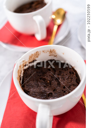 Freshly baked chocolate mug cakes in white cups. Freshly baked chocolate mug cakes in white cups. 102250599