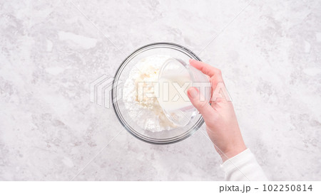 Flat lay. Step by step. Mixing ingredients in a glass mixing bowl to prepare cream cheese frosting. 102250814