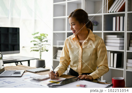 A female accountant working in her office, reviewing accounting sales reports. 102251054