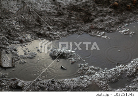 Rainy soil ground. Defocus water rain droplet splashes in puddle on ground. Dark, sad, moody and dramatic background. Water ripple texture. Out of focus Rainy soil ground. Defocus water rain droplet splashes in puddle on ground. Dark, sad, moody and dramatic background. Water ripple texture. Out of focus 102251348