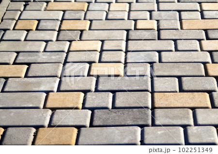 Gray and yellow pavement bricks for pavement road on the floor. Defocus brick tiles background. Stack paving stones. Gray design copy space. Brick background. Out of focus 102251349