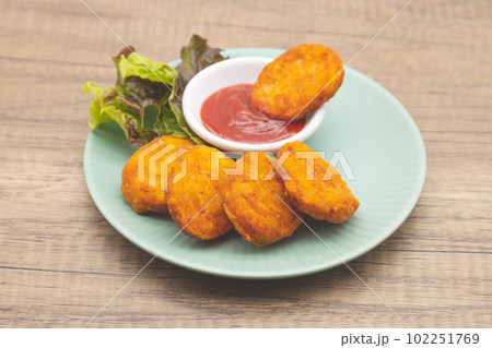 チキンナゲットとケチャップが青い皿に盛り付けられている 102251769