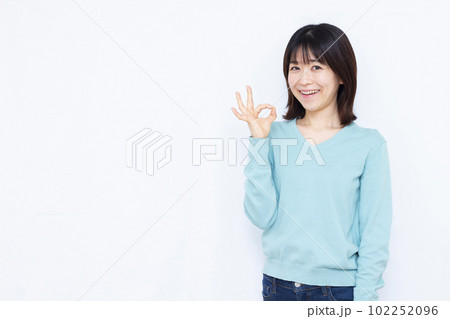 白い背景の前でOKサインをしている30代の女性 白い背景の前でOKサインをしている30代の女性 102252096