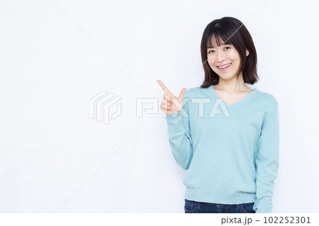 白い背景の前で人差し指を立てる30代の女性 白い背景の前で人差し指を立てる30代の女性 102252301