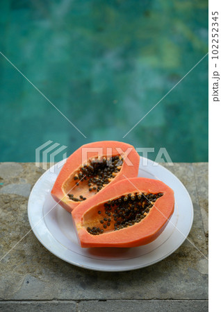 Two halves of peeled papaya in plate near swimming pool Two halves of peeled papaya in plate near swimming pool 102252345