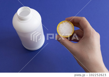 Woman Hand Holds Dosage Of Pipe Cleaner Granules. Removal Of Blockage In Sink, Shower With Special Remedy With Chemicals. Cleaning Clog In Kitchen And Bathroom. White Plastic Bottle On Background Woman Hand Holds Dosage Of Pipe Cleaner Granules. Removal Of Blockage In Sink, Shower With Special Remedy With Chemicals. Cleaning Clog In Kitchen And Bathroom. White Plastic Bottle On Background 102252623