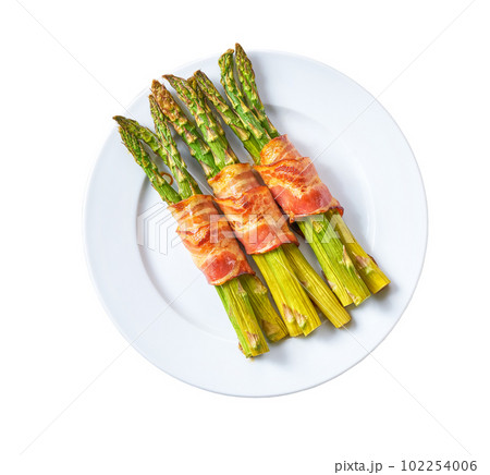 Plate with baked appetizer, bundle of green asparagus wrapped in bacon isolated on a white background. Top view. Plate with baked appetizer, bundle of green asparagus wrapped in bacon isolated on a white background. Top view. 102254006