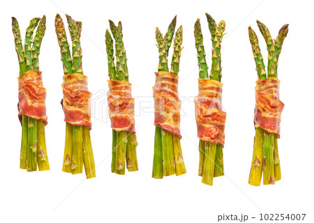 baked bundle of green asparagus wrapped in bacon isolated on a white background. baked bundle of green asparagus wrapped in bacon isolated on a white background. 102254007