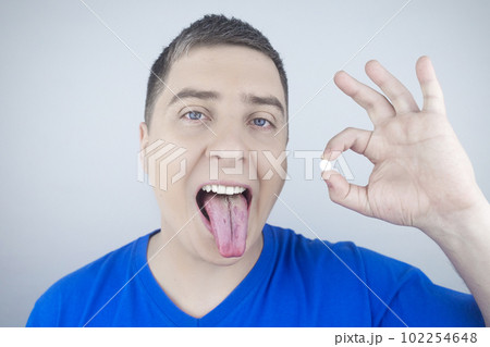 Oral probiotics. A man puts a pill with beneficial bacteria on his tongue. Dysbacteriosis and imbalance of beneficial and harmful microorganisms in the mouth. Increase immunity and improve health. Oral probiotics. A man puts a pill with beneficial bacteria on his tongue. Dysbacteriosis and imbalance of beneficial and harmful microorganisms in the mouth. Increase immunity and improve health. 102254648