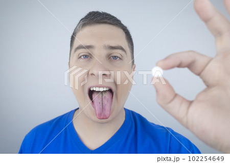 Oral probiotics. A man puts a pill with beneficial bacteria on his tongue. Dysbacteriosis and imbalance of beneficial and harmful microorganisms in the mouth. Increase immunity and improve health. 102254649