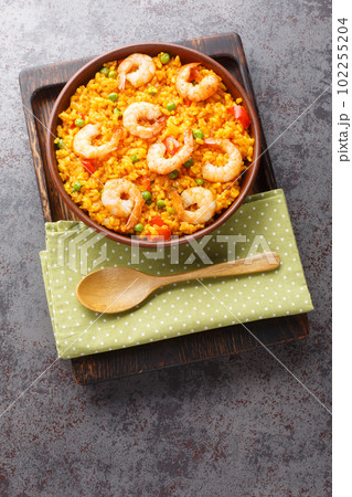Flavorful Spanish yellow rice and shrimp with vegetables and spices closeup on the plate. Vertical top view 102255204