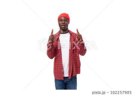 handsome joyful dark-skinned man in a casual plaid shirt points a finger at an advertisement on a handsome joyful dark-skinned man in a casual plaid shirt points a finger at an advertisement on a 102257985