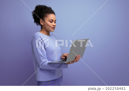 20s young afro hair brunette woman with laptop to work on blue background 20s young afro hair brunette woman with laptop to work on blue background 102258481