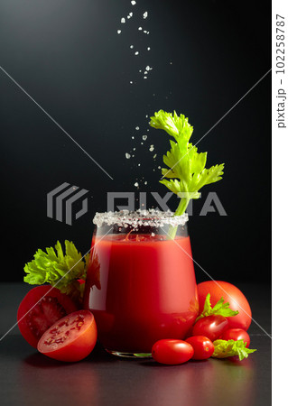 Sea salt is poured into a glass of tomato juice with celery. Sea salt is poured into a glass of tomato juice with celery. 102258787