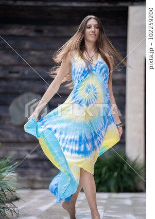 A young beautiful woman model is smiling, a young woman is walking down the street, her dress is blowing in the wind A young beautiful woman model is smiling, a young woman is walking down the street, her dress is blowing in the wind 102259200