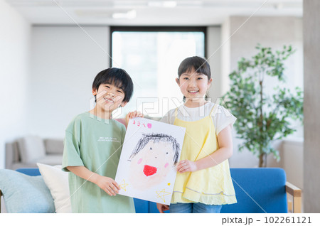 ママの似顔絵を見せる姉弟 ママの似顔絵を見せる姉弟 102261121