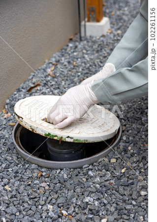 一戸建て住宅の外の汚水桝を掃除しているところ 102261156